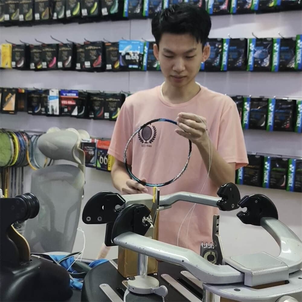 Teh Zi Han inspecting strings and finishing a badminton racket