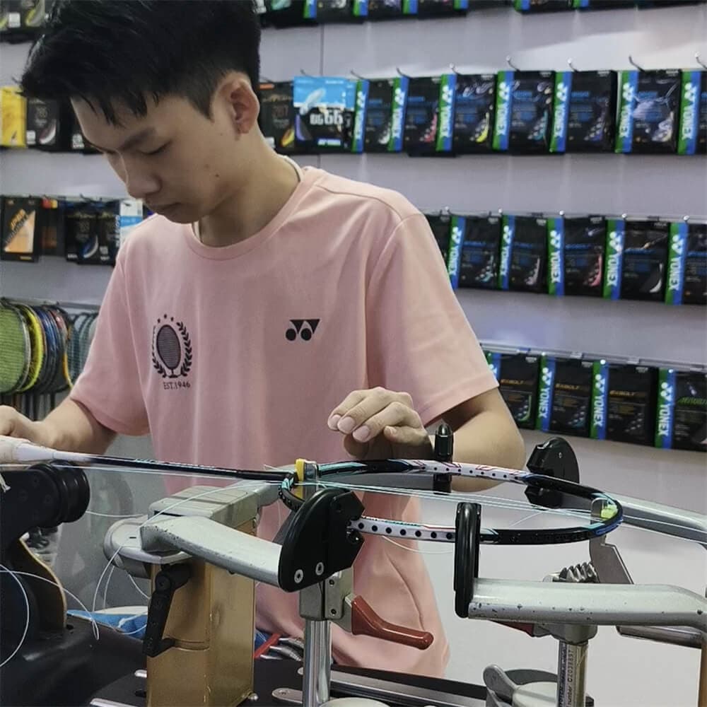 Teh Zi Han operating an electronic badminton racket stringing machine
